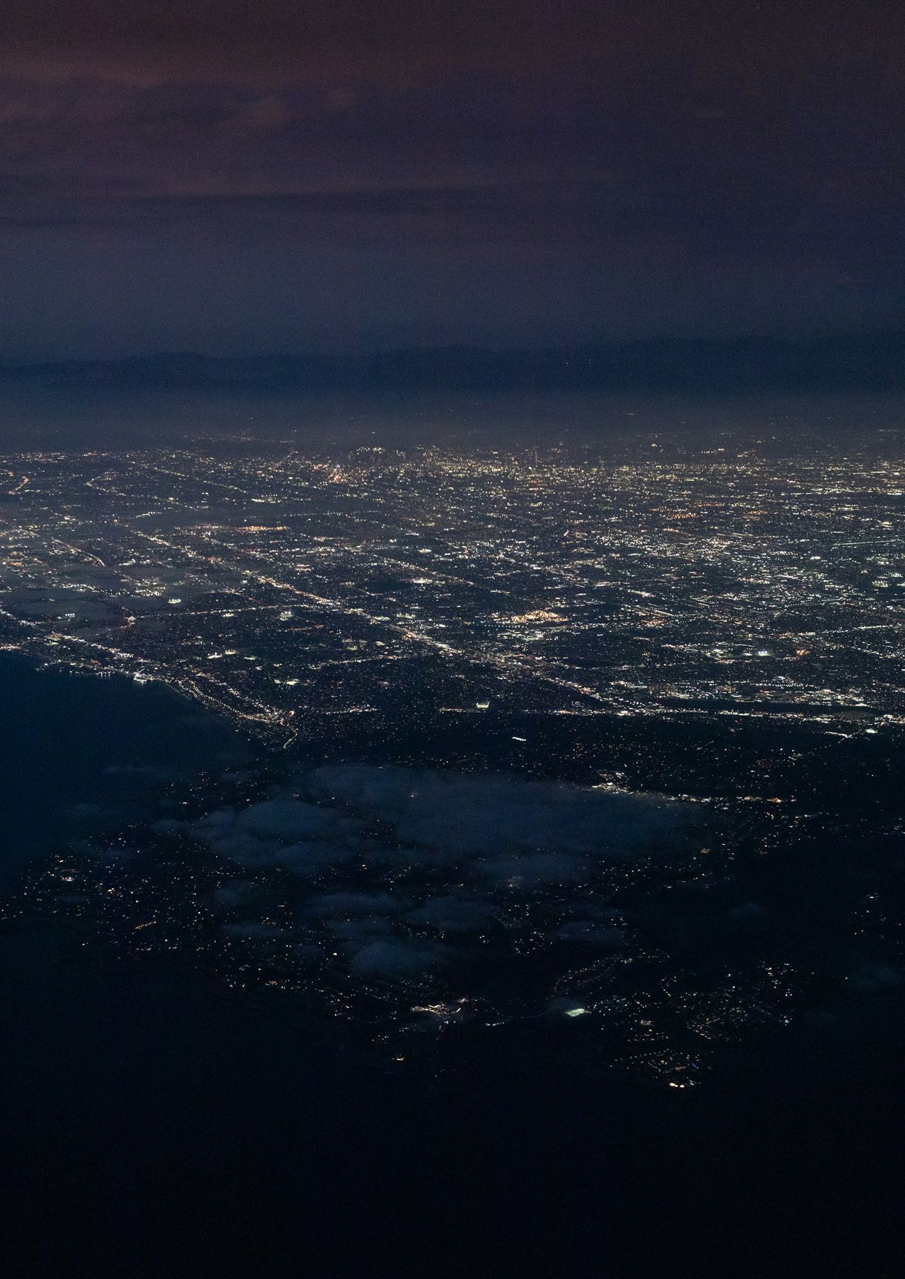 Los Angeles at night from the air, the coastline traced in lights