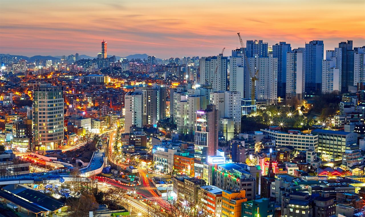 Seoul at dusk, city lights coming on beneath an orange sky