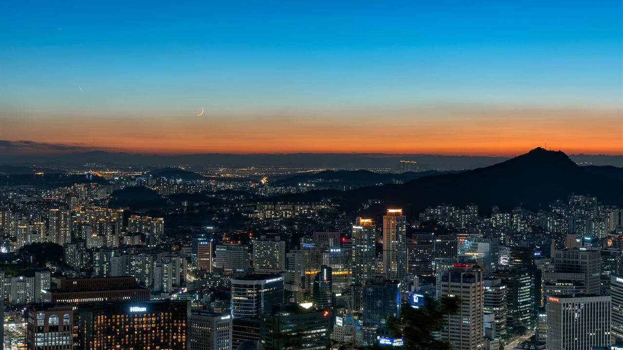 Seoul’s lights under a thin crescent moon, seen from Namsan