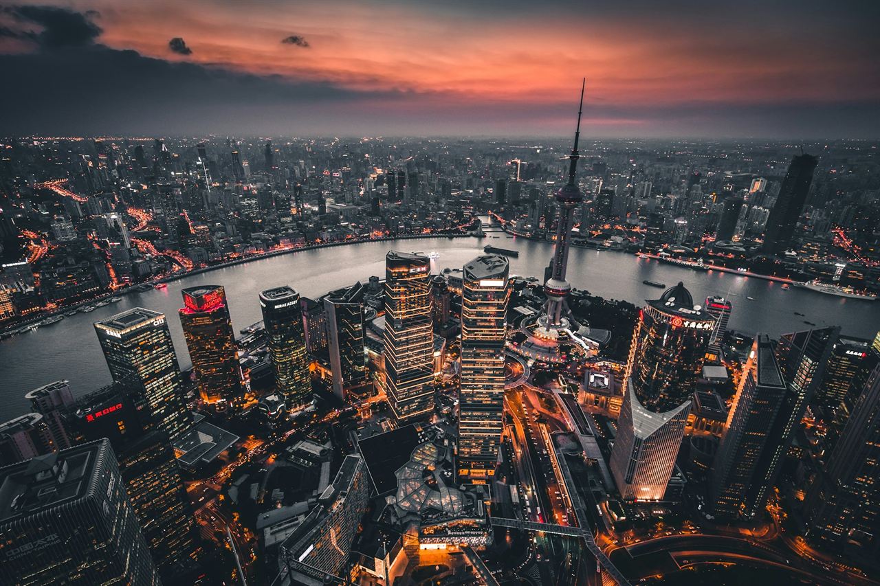 Shanghai from above at golden hour, the Huangpu River curving through the towers
